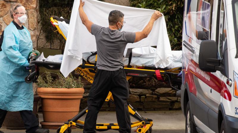 Healthcare workers transfer a patient into an ambulance outside the Life Care Center of Kirkland