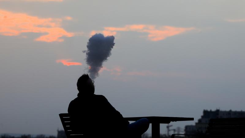 A man is smoking e-cigarette. 
