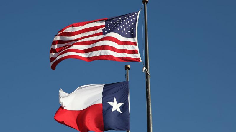 Texas and American flags flying at an Austin library