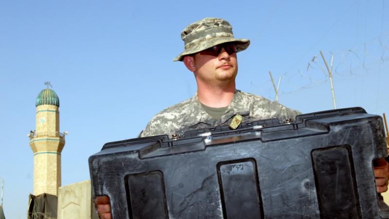 An American soldier in Iraq works in 2009 while the Muslim call to prayer sounds from a minaret
