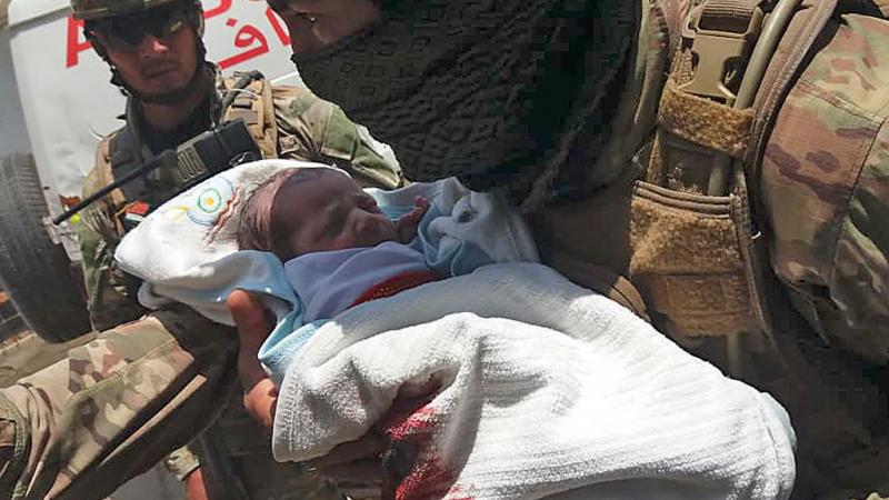 Afghan special forces soldier carrying a newborn from the wreckage of Tuesday's maternity ward attack