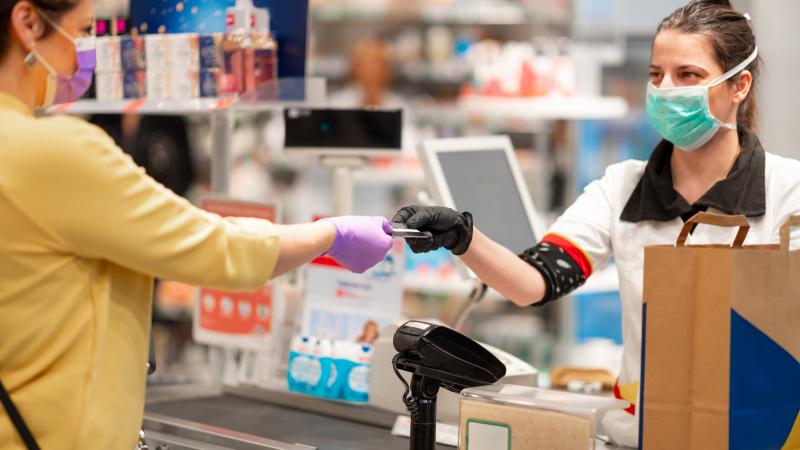 A shopper and a cashier in surgical masks