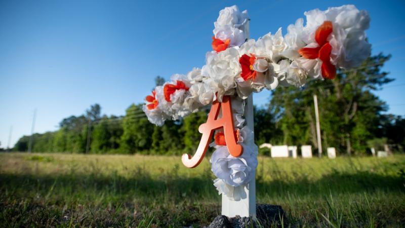 Cross with flowers at entrance to neighborhood where Ahmaud Arbery was killed