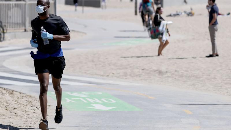A jogger in Venice Beach, California wears a mask 