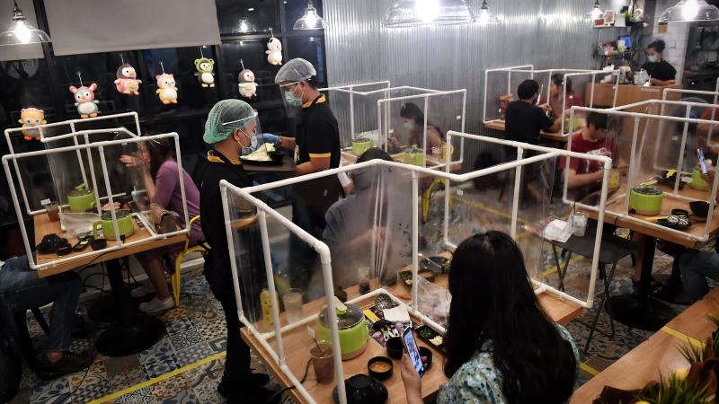 People eat in between plastic partitions, set up in an effort to contain any spread of the COVID-19 coronavirus, at the Penguin Eat Shabu hotpot restaurant in Bangkok on May 5, 2020. 