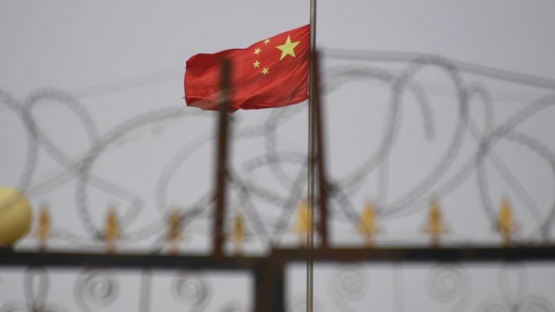 The Chinese flag flies behind razor wire at a housing compound in China's western Xinjiang region.