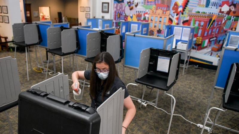 A poll worker sanitizes voting booths in Denver, Colorado, June 30