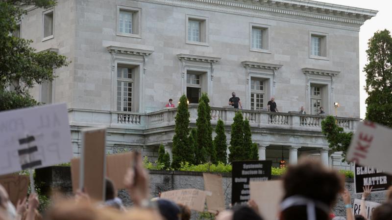 Security personnel stand on the balcony the home of Mark and Patricia McCloskey who gained national attention after brandishing firearms at protesters as they stormed passed their home
