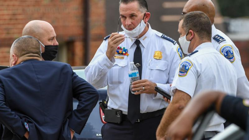 Police Chief stands with other officials investigating shooting.