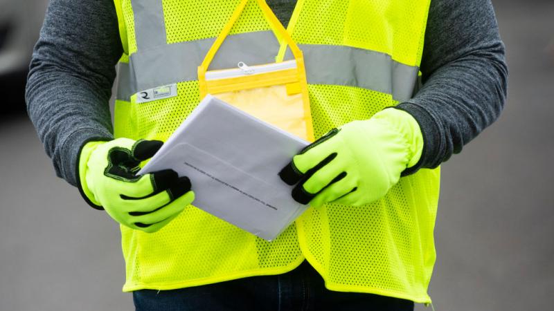 Staff holding ballot with gloves on.