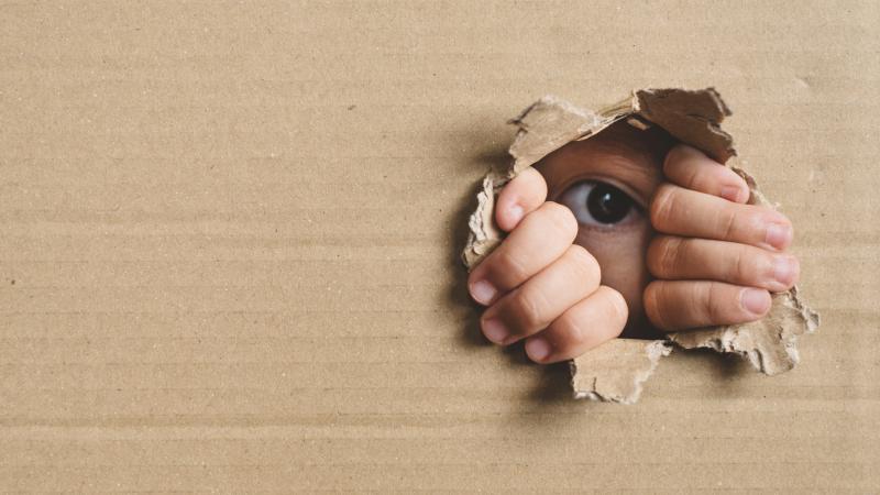 Little Girl Peeking From A Hole On Cardboard Box
