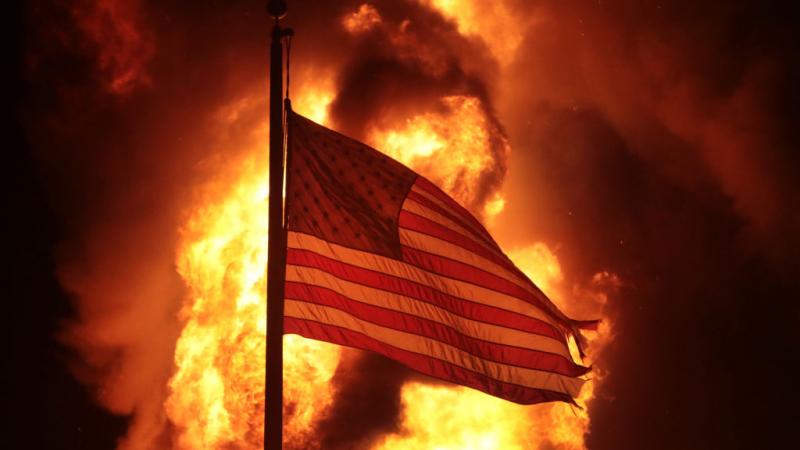 Flag in front of burning building during rioting in Kenosha, Wisconsin on August 24, 2020