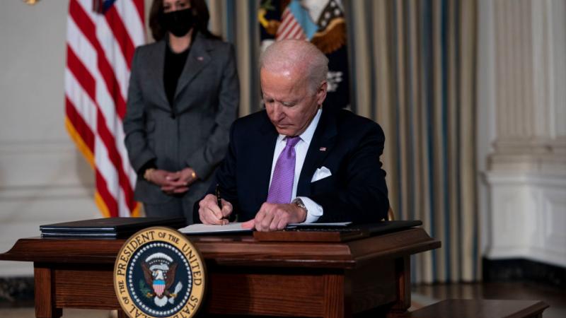 Vice President Kamala Harris looks on as U.S. President Joe Biden signs executives orders