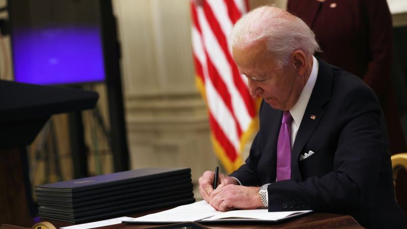 U.S. President Joe Biden signs an executive order during an event in the State Dining Room of the White House January 21, 2021 in Washington, DC.