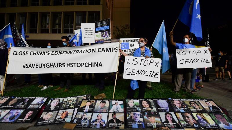 Protesters stand behind a display of photographs of prominent Uighur intellectuals detained by China as they gather across from the Chinese Consulate in Los Angeles on October 1, 2020 during a global day of action called by "Resist China" (#ResistChina), a global campaign against the regime of the Chinese Communist Party.