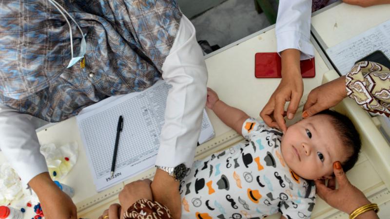 Medical staff work with infant patient. 