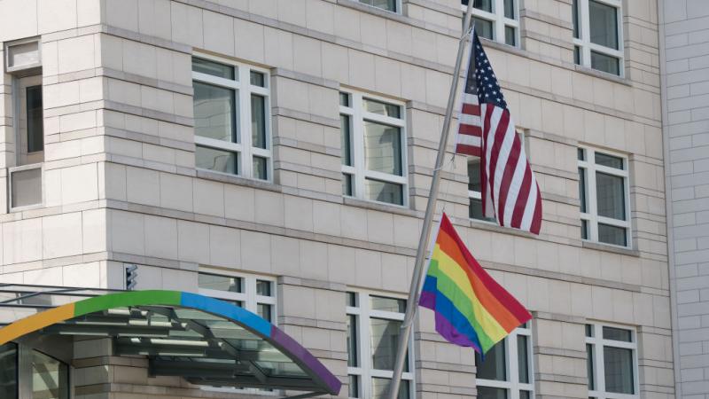 A rainbow flag hangs under a US flag at the US embassy in Berlin, 2019.