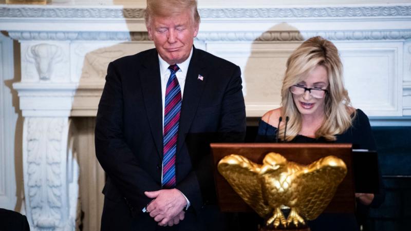 Then-President Trump listens as Pastor Paula White leads a prayer in 2018
