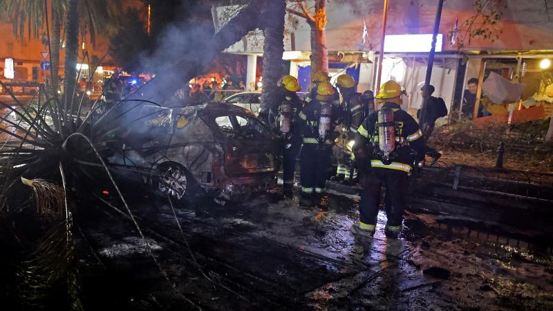 Israeli firefighters inspect a destroyed car in the town of Holon near Tel Aviv, on May 11, 2021, after rockets were launched towards Israel from the Gaza Strip controlled by the Palestinian Hamas movement.