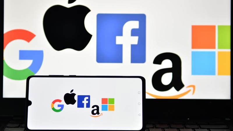 Big Tech: An illustration picture taken in London on December 18, 2020 shows the logos of Google, Apple, Facebook, Amazon and Microsoft displayed on a mobile phone and a laptop screen.