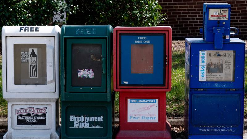 A Baltimore Sun newspaper bin(R) stands with others in Baltimore, Maryland on March 11, 2021.