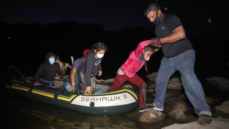 Guided by coyotes piloting an inflatable raft, migrants cross the Rio Grande River and arrive on American soil on April 23, 2021 in Roma, Texas.