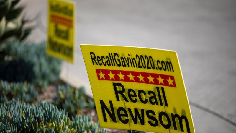 Signage is seen near a booth where conservative activists gather signatures in a recall effort against California Governor Gavin Newsom near Pasadena City Hall, in Pasadena, California on February 28, 2021.