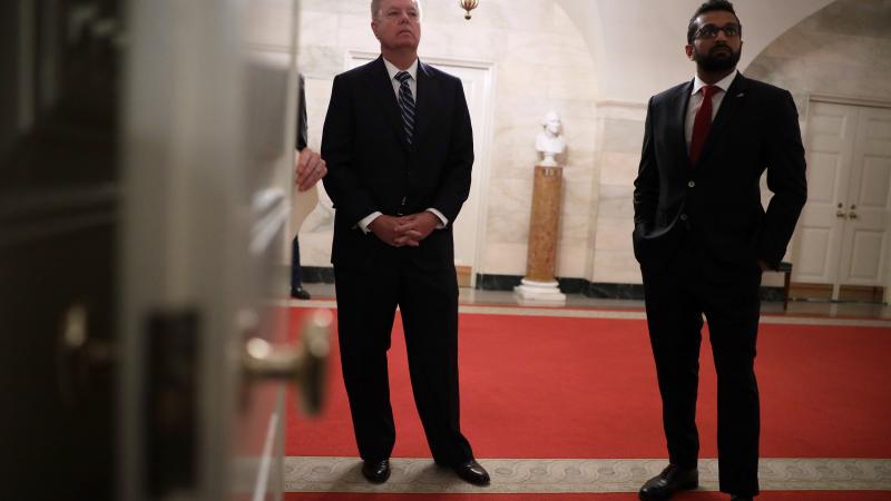 U.S. Sen. Lindsey Graham (R-SC) (L) and National Security Council Senior Director of Counterterrorism Kashyap "Kash" Pramod Patel listen as U.S. President Donald Trump makes a statement in the Diplomatic Reception Room of the White House October 27, 2019 in Washington, DC.