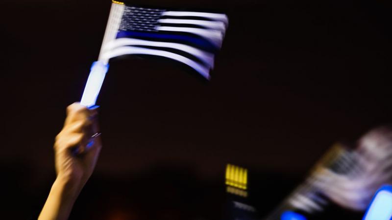 A person waves a thin blue line flag at the United by the Blue Line Vigil organized by the El Paso Police Wives and Family Support Organization