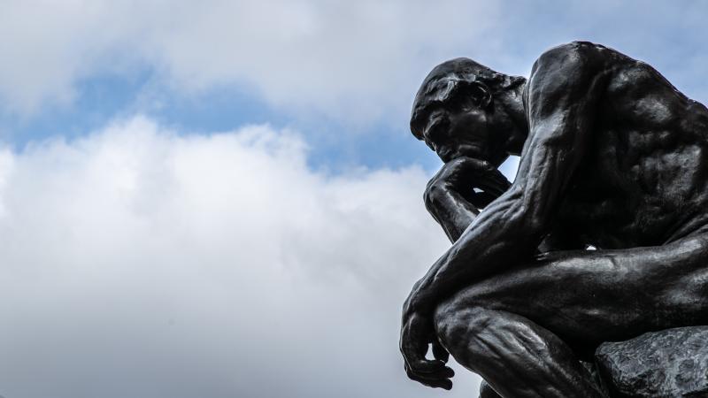 The sculpture "The Thinker" ("Le Penseur") by the sculptor Auguste Rodin can be seen against a cloudy sky.