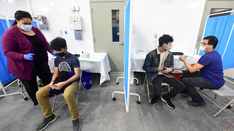 Brothers Ames, 17 (2nd L) and Amiel, 19 (2nd R) arrive to receive their first dose of the Pfizer Covid-19 vaccine at the Blood Bank of Alaska in Anchorage on March 19, 2021.