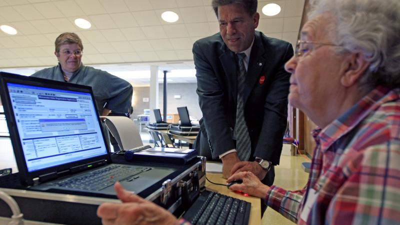 Laura Ronbeck, City of Minnetonka Deputy City Clerk and (right) Donna Kamm, election official, showed Minnesota Secretary of State Mark Ritchie a electronic poll book used in 11/03/09 election.