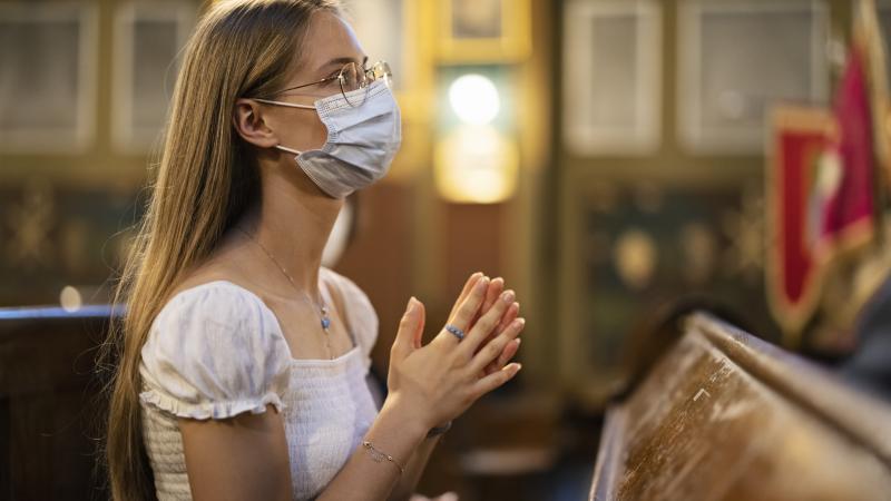 Girl praying in church with face mask