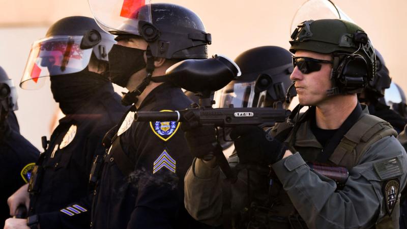  A pepper ball (L), exits the barrel of a San Diego Police Department (SDPD) officer's Tippmann FT-12 paintball gun while firing pepper balls towards counter-protesters as they stand against demonstrators holding a "Patriot March" demonstration in support of US President Donald Trump on January 9, 2021