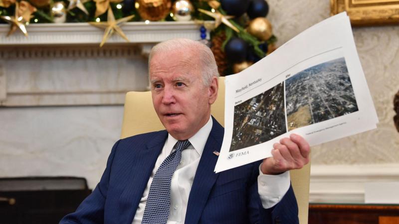Joe Biden holds pictures of tornado damage, Washington, D.C., Dec. 13, 2021