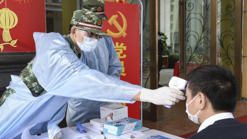 Chinese soldier checks man's temperature