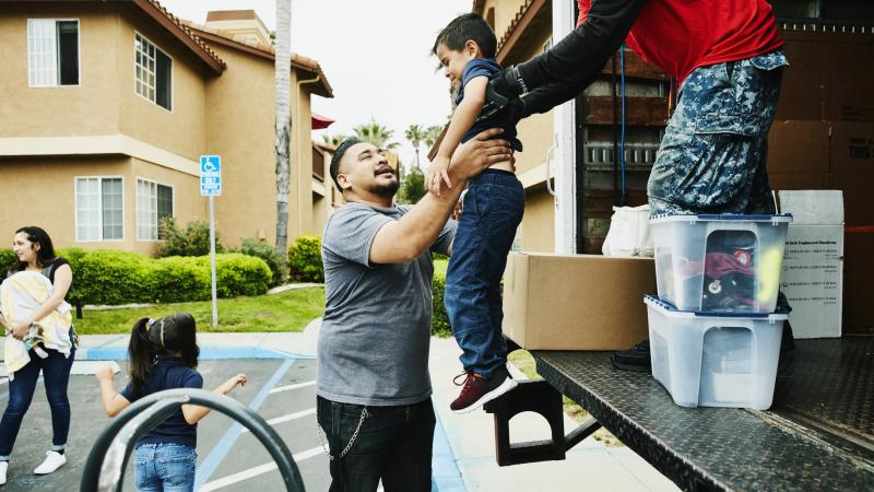 Mover handing young boy to father