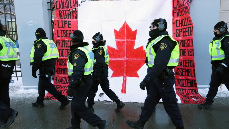 Police officers walk past "Freedom Convoy" protest poster, Ottawa, Canada, Feb. 7, 2022