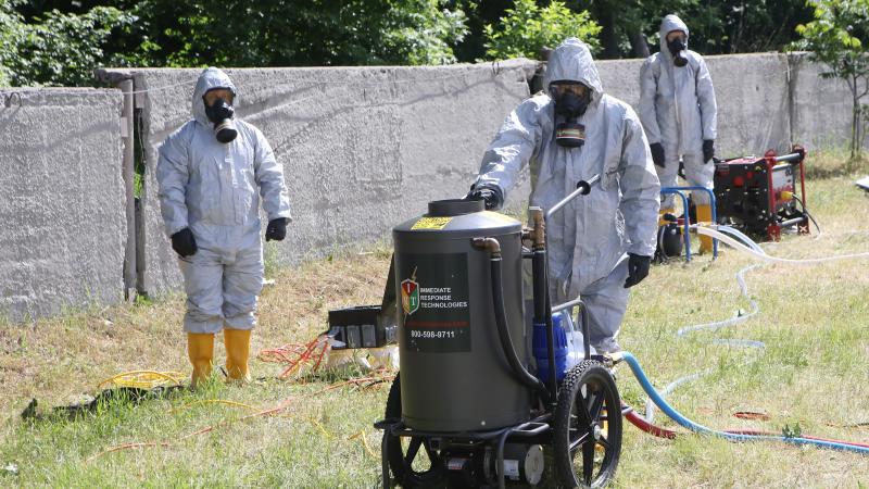 Ukrainian State Emergency Service members in protective suits with gas masks, June 2021