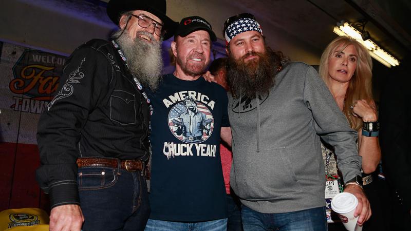 Actor Chuck Norris poses with Si and Willie Robertson, of Duck Dynasty, at the drivers meeting prior to the NASCAR Sprint Cup Series AAA Texas 500 