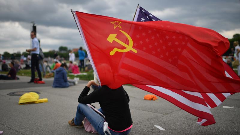 A protester waves flags of the Soviet Union and of the USA prior to a demonstration against lockdown measures and government policy during the coronavirus crisis on May 23, 2020 in Munich, Germany.