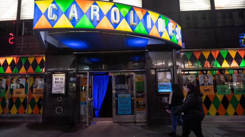 People walk past the newly reopened Caroline's Comedy Club in Times Square on Memorial Day weekend on May 29, 2021 in New York City.