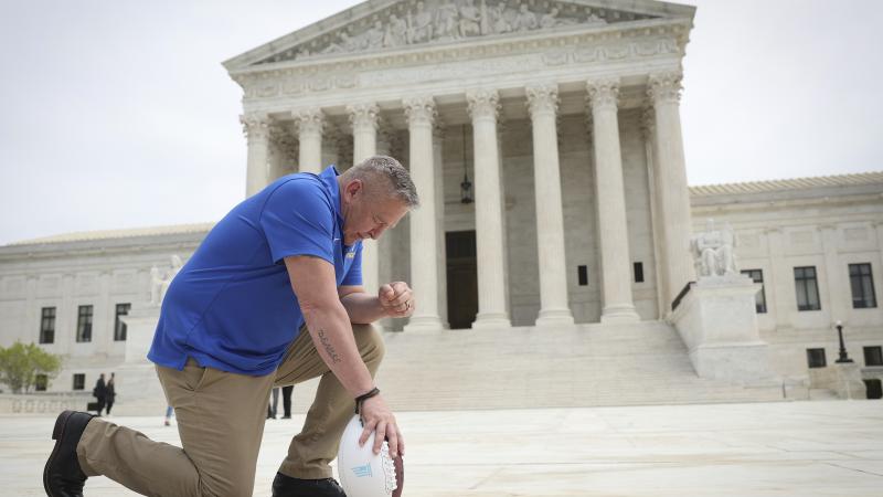 Former Bremerton High School assistant football coach Joe Kennedy takes a knee in front of the U.S. Supreme Court after his legal case, Kennedy vs. Bremerton School District, was argued before the court on April 25, 2022 in Washington, DC.