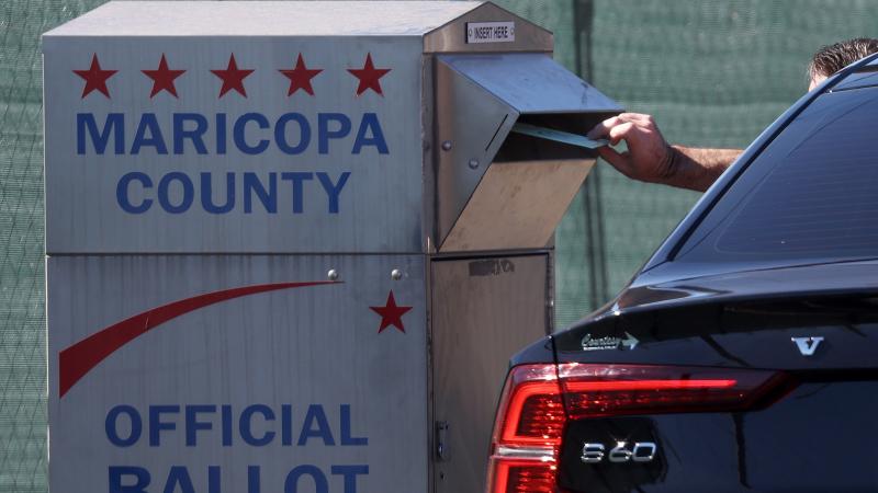 A voter drops their ballot into a drop box outside of the Maricopa County Tabulation and Election Center on November 06, 2022 in Phoenix, Arizona.