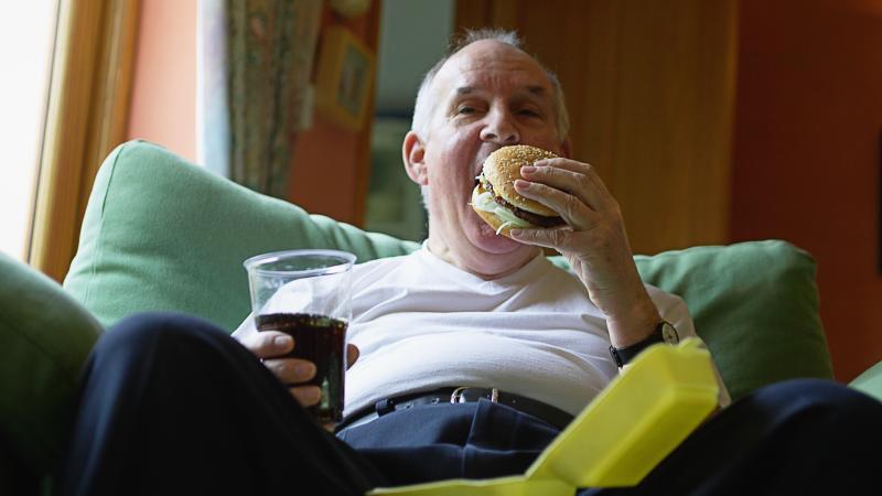 Overweight man eating burger