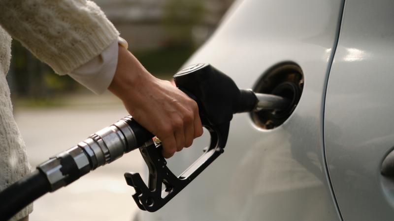 A woman using a gas pump to refuel vehicle during energy crisis
