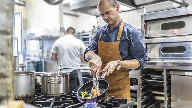Professional chef cooks steak with fresh wegetable in the restaurant on pan. 