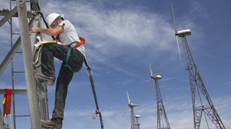 A construction worker in California ascends a wind turbine tower