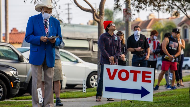People stand in line to vote as the sun rises at the Main Street Branch Library vote center on November 3, 2020 in Huntington Beach, California.