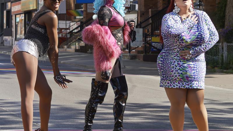 Drag queens posing on rainbow pavement on city street